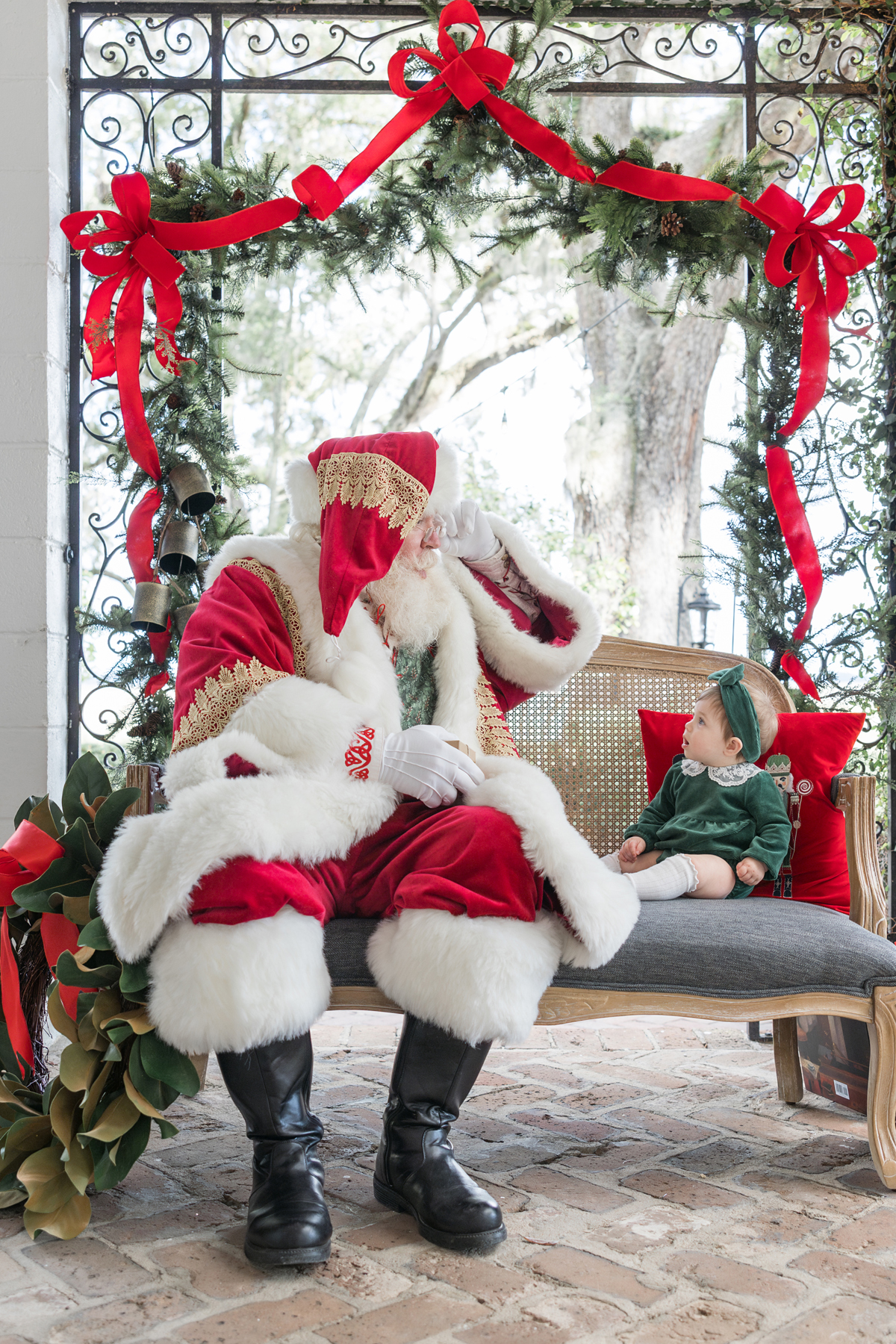 Santa and a baby girl look at each other in Christmas portrait set up at HollyOaks on the Marsh.