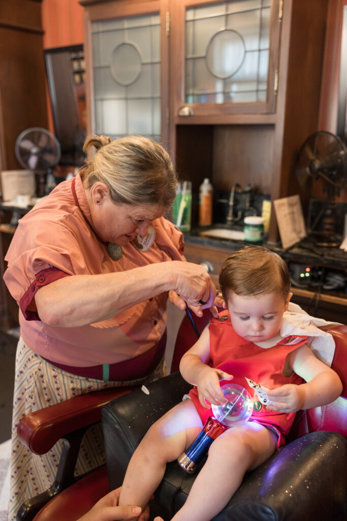 A toddler with a lightup toy has his first haircut