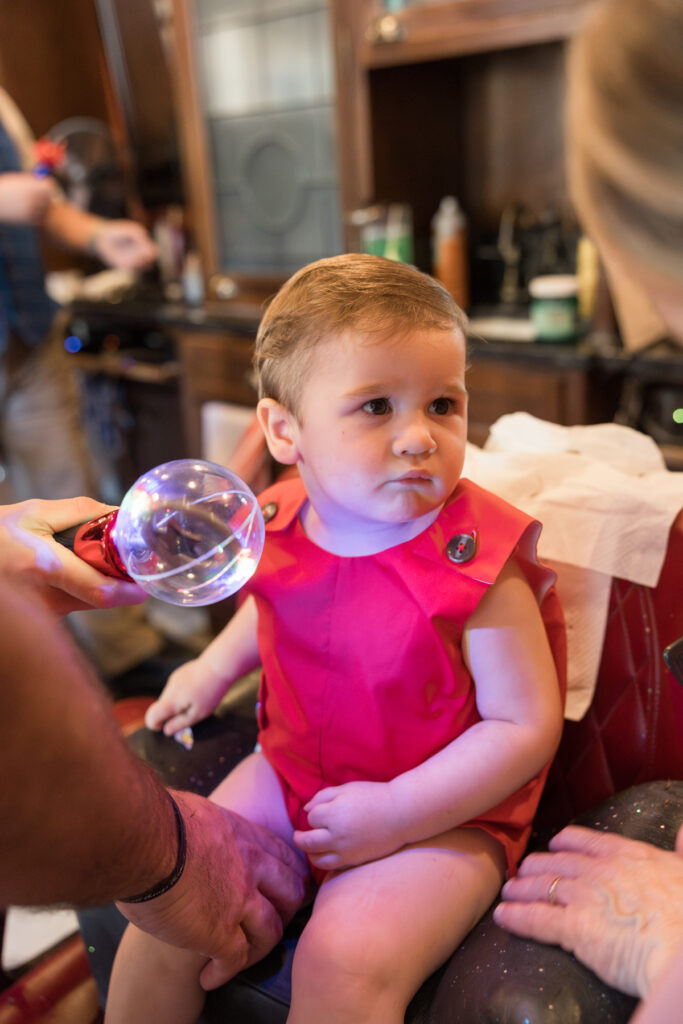 A toddler boy looks unamused as someone offers him a lightup toy.