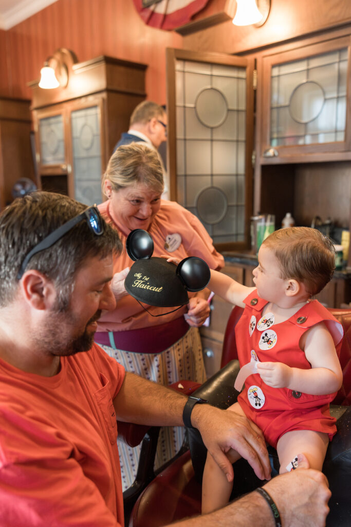 At the Harmony Barbershop, the hairstylist holds the Mickey hat for Savannah family photographer Tiffany Bradley's little boy.