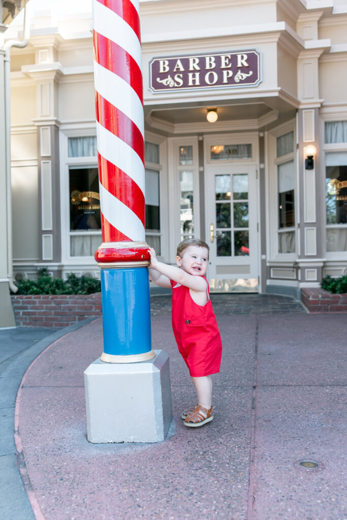 Boy in red outfit in front of barbershop