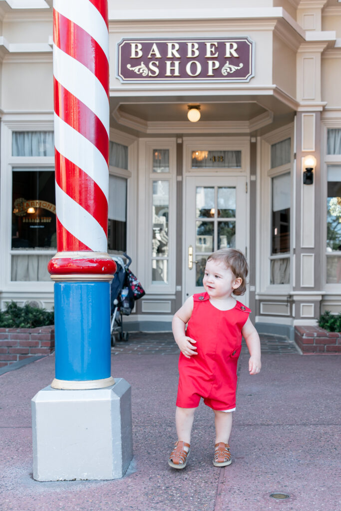 A little boy before his haircut in front of the barbershop in Disney.