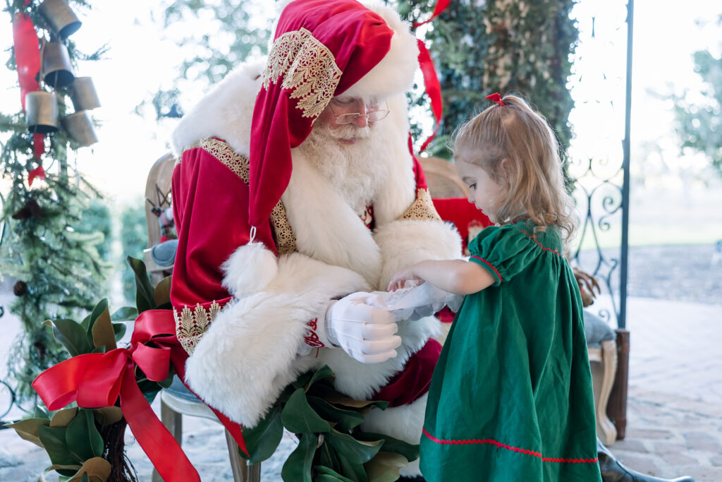 A little girl opening a gift with Santa's help at HollyOaks on the Marsh in Savannah.