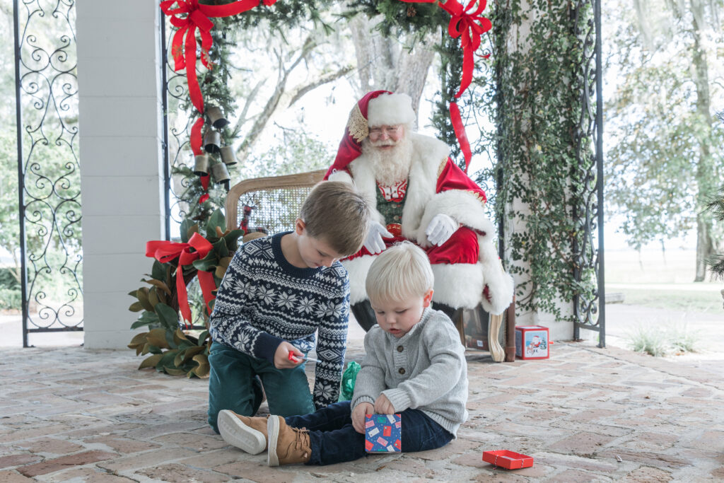 Two little boys opening gifts in front of Santa at HollyOaks on the Marsh in Savannah, GA.