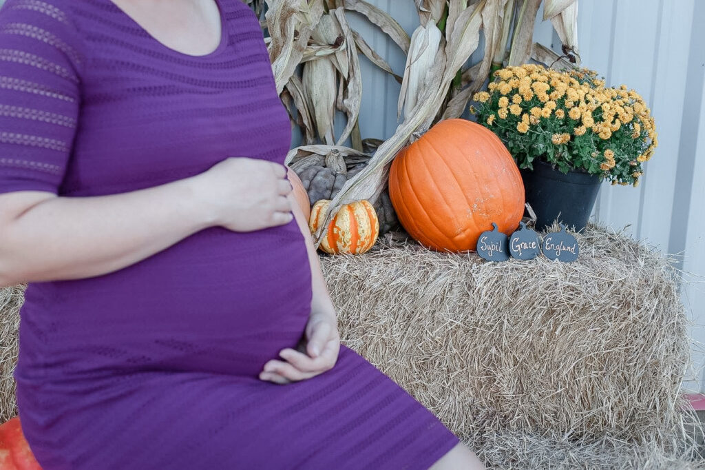 A mom to be cradles her baby bump at Madrac Farms pumpkin patch.