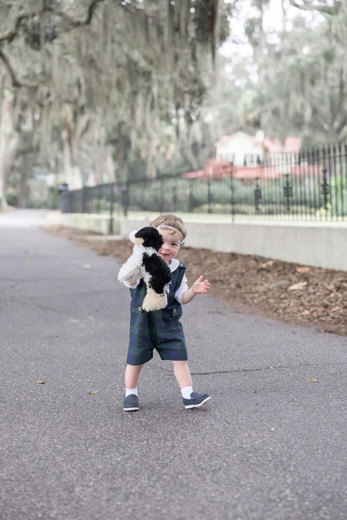 A little boy smiles with his stuffed puppy while at his family's fall photography session. 