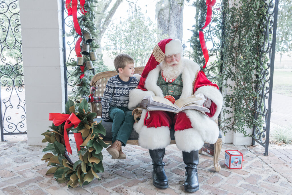 Santa and a little boy sitting on a bench reading a book.