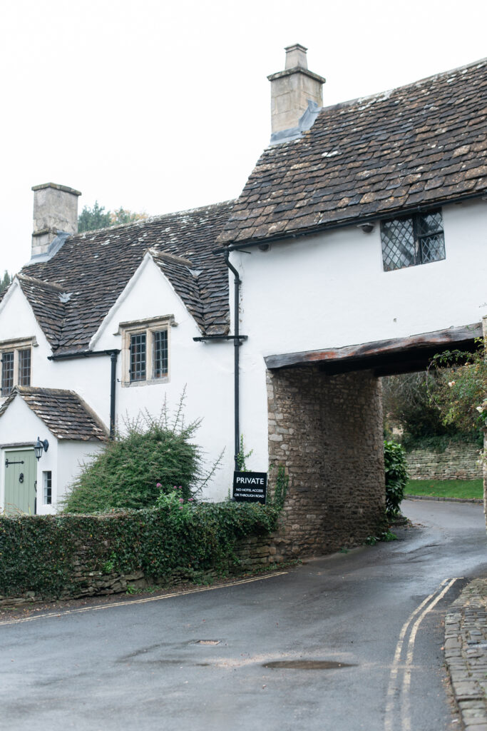 An old white building with a cut through for cars. 