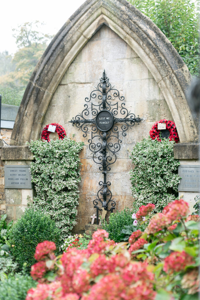 A monument with a cross, surrounded by red colored hydrangeas. 