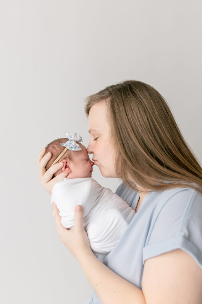 A side profile shot of a mom kissing her newborn's nose during an in-studio session with Savannah maternity photographer Tiffany Bradley.