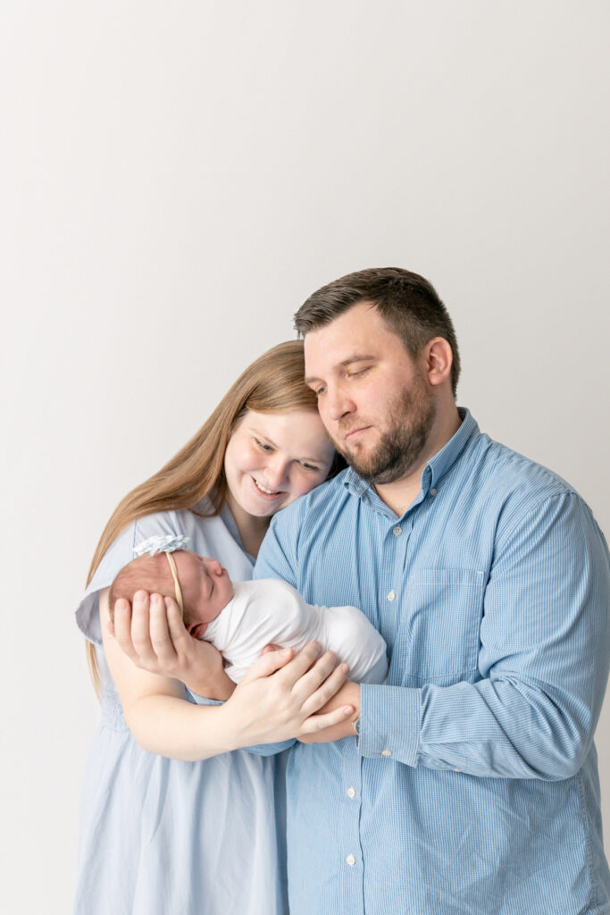 Two parents smile down on their baby girl during a session with Tiffany Bradley, a Savannah maternity and newborn photographer. 