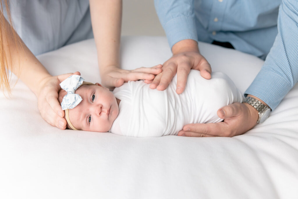 A newborn baby girl looks at the camera while her parents hold on to her during an in-studio newborn session in Savannah, Georgia.