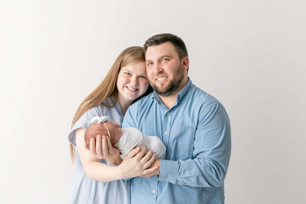 Two new parents smile with their baby girl during a studio newborn session with Savannah maternity photographer, Tiffany Bradley.