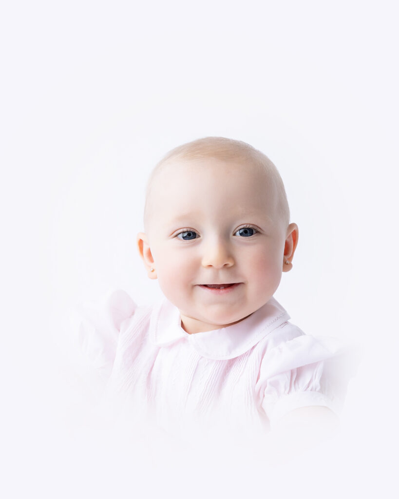 Baby girl smiles in a traditional heirloom portrait.