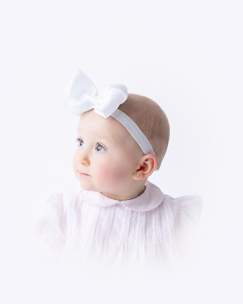 Baby girl with headband looks to her right during heirloom session in Savannah.