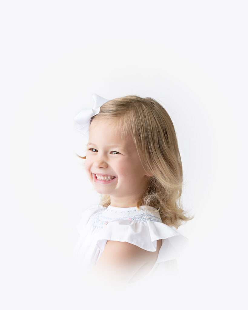 Two sisters, each posing in white dresses on white backgrounds for their heirloom portraits.