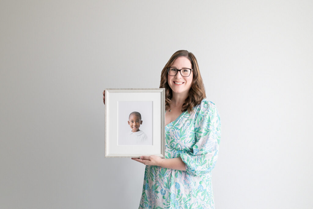 Full-service Savannah Photographer, Tiffany Bradley holds a framed fine art portrait of an heirloom portrait session.