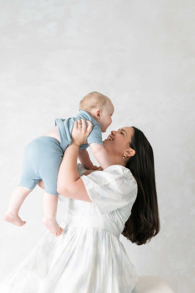 A mom, laughing, brings her baby in close to her face.