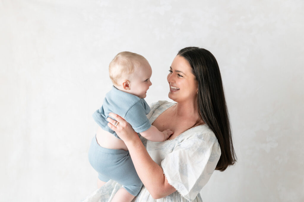 A mom holds her baby boy, dressed in blue during an in-studio photography session in Savannah, Georgia.