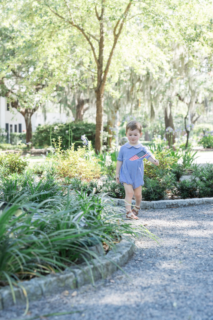 A little boy waves an American flag while wearing a blue and white striped bubble from Littles on Liberty in Kavanaugh Park in Savannah, Georgia.