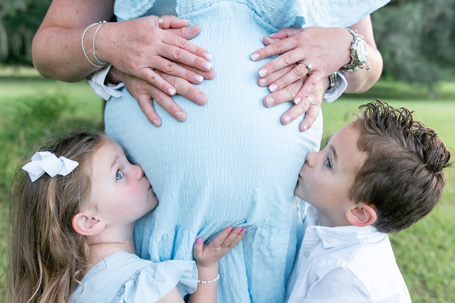 a maternity photography session in savannah ga with two kids kissing sweet baby