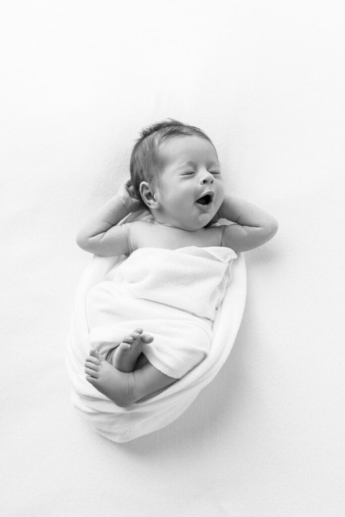 A black and white portrait of a newborn baby boy mid yawn during a Savannah, Ga newborn photography session with Tiffany Bradley Photography.