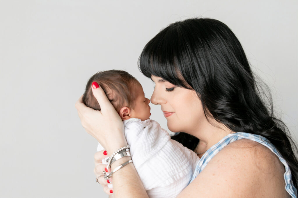 A mom and newborn baby nose to nose in a portrait from their session with Tiffany Bradley newborn photographer in Savannah GA.