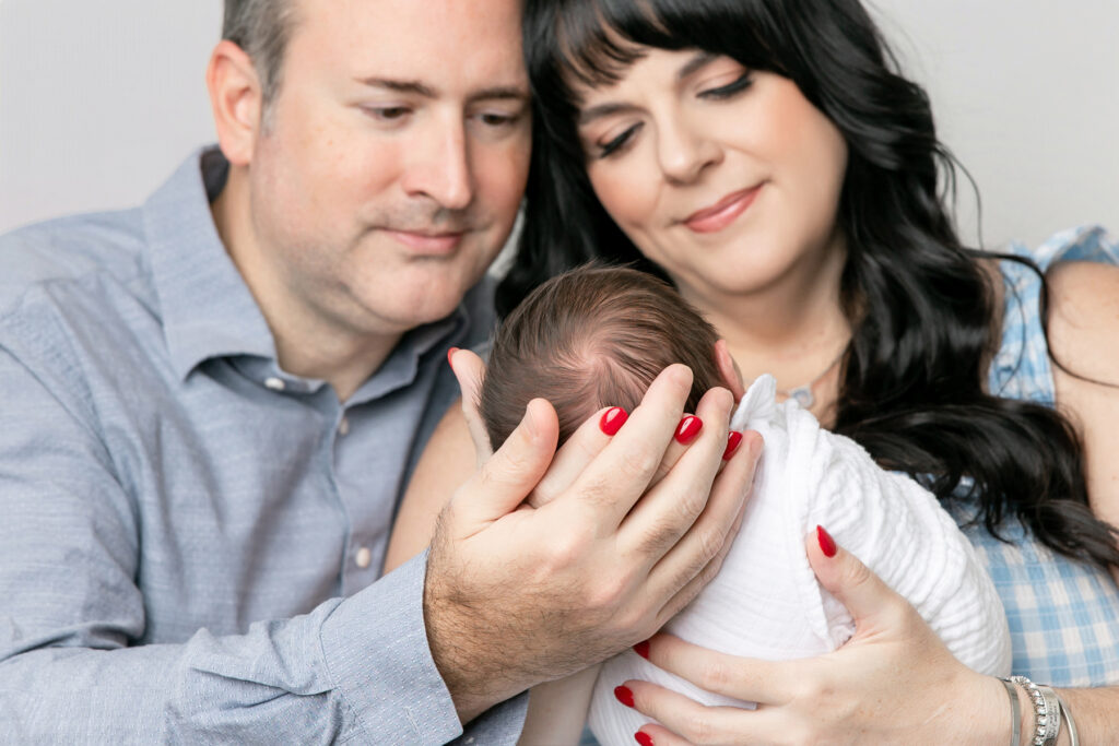 A close up picture of a mom and dad looking down at their newborn in Savannah photography studio Tiffany Bradley Photography.