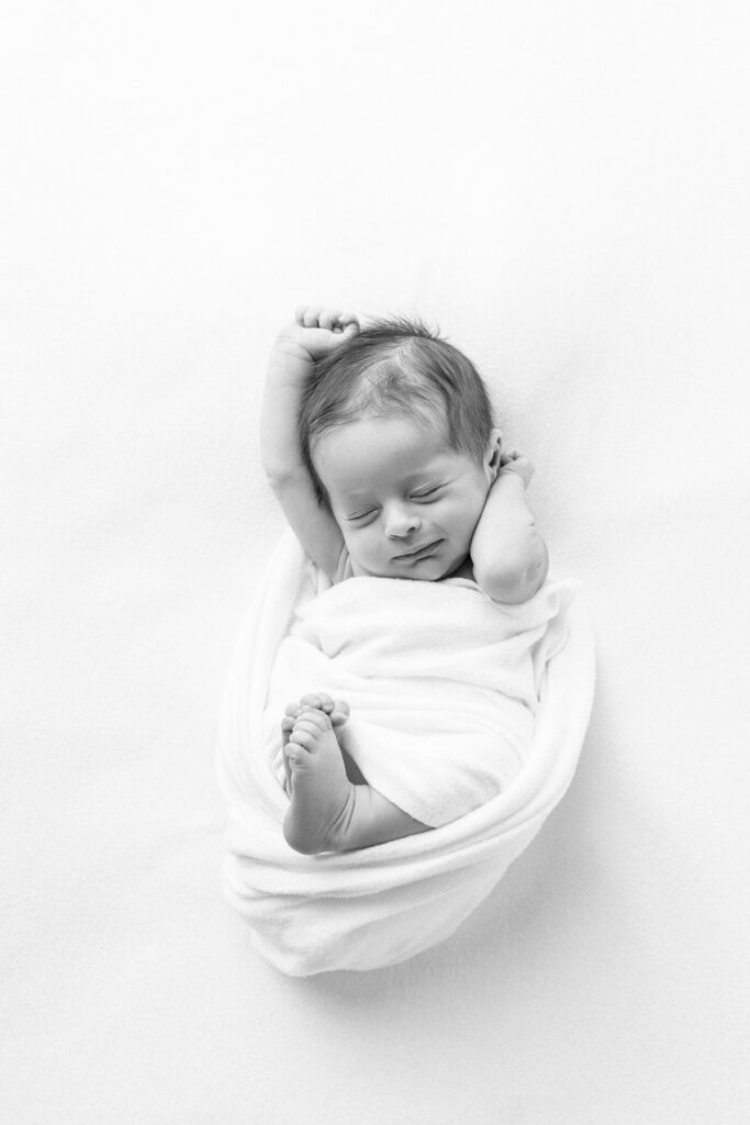 A black and white portrait of a newborn baby boy mid stretch during a Savannah, Ga newborn photography session with Tiffany Bradley Photography.