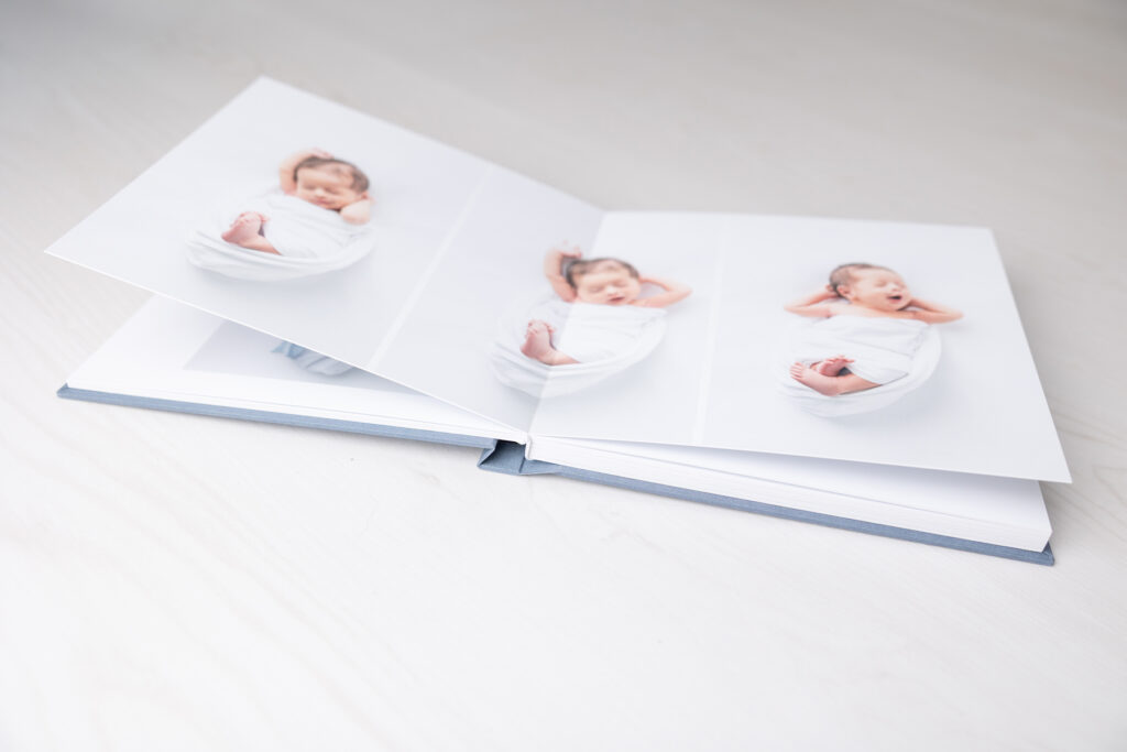 A photo album open to a page with three images of a baby stretching and yawning during his Savannah photography session.