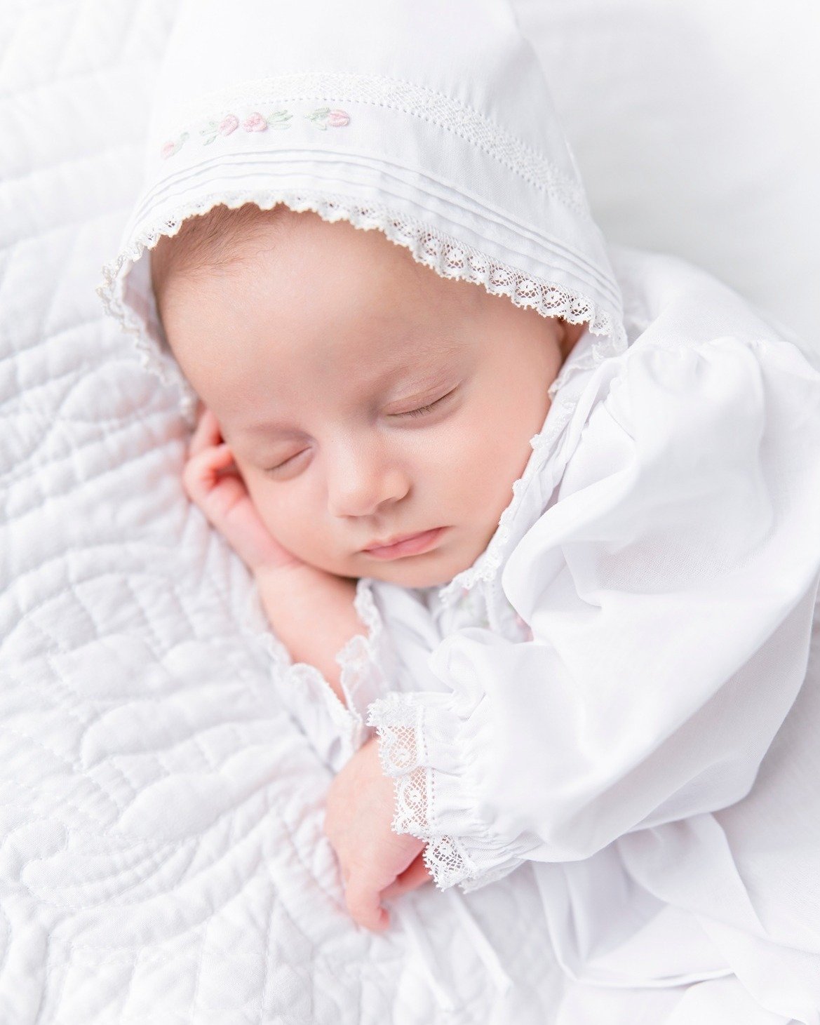 A sweet newborn in a white dress and bonnet sleeps quietly and safely as this Savannah-based photographer ensures all newborn safety tips are being followed.