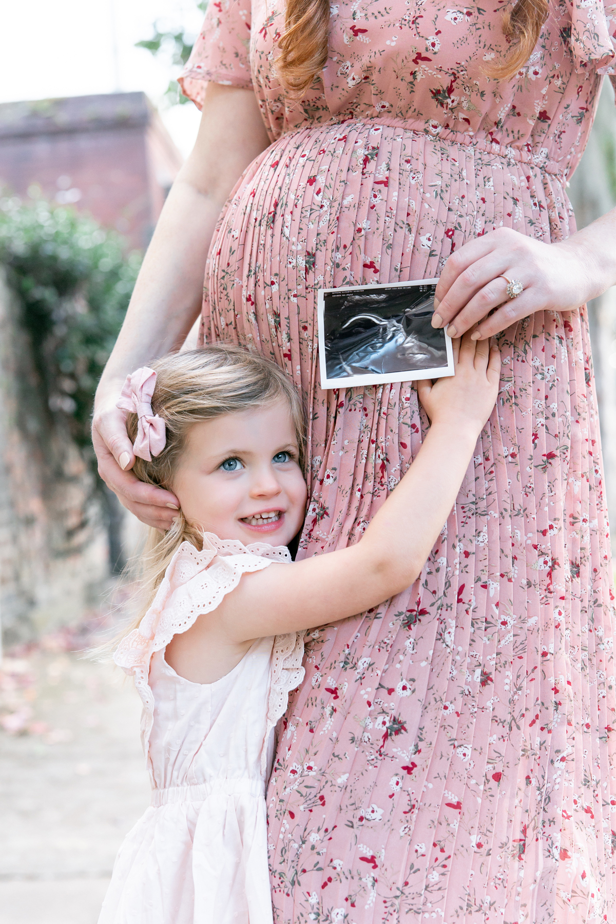 A little girl hugs her mom's pregnant belly with an ultrasound also in the frame. Maternity pictures Savannah, GA.