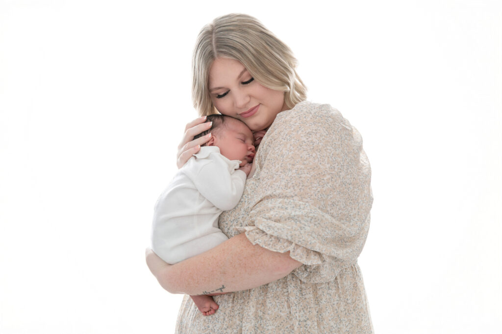 Mother and newborn baby photographed together against a softly backlit white background in a Savannah, GA newborn photography studio.