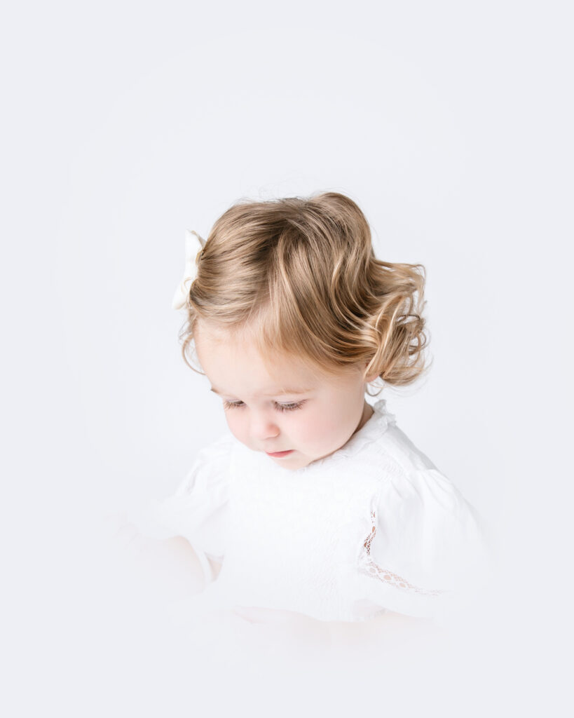 A toddler girl looks down in profile during her heirloom portrait session in Georgia.