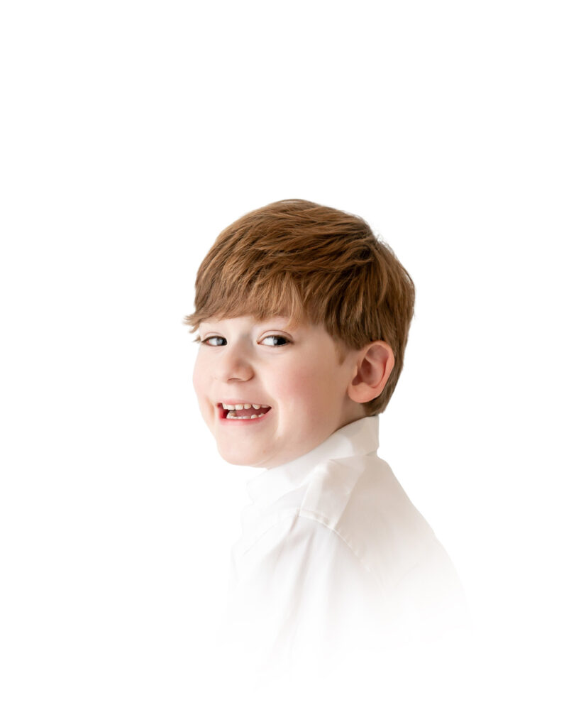 A boy smiles in front of a white background during a studio photography session in Savannah.