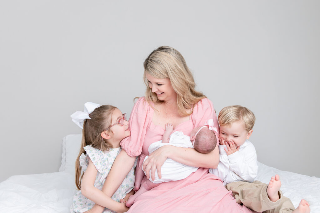mother holding newborn baby with older siblings during studio newborn session in Savannah Georgia