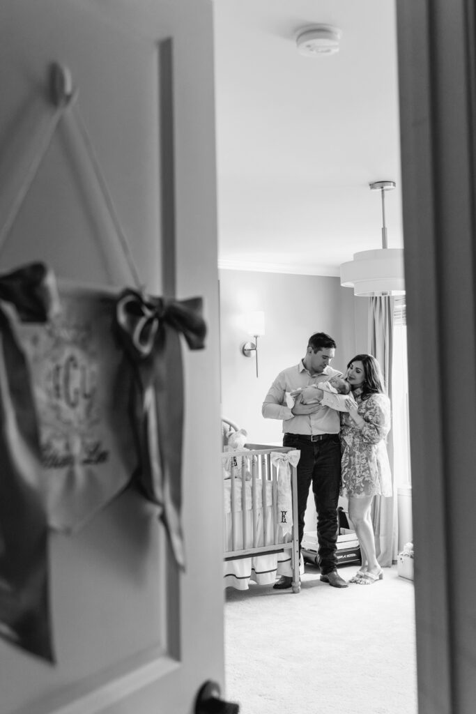 black and white image of parents standing in their baby's nursery