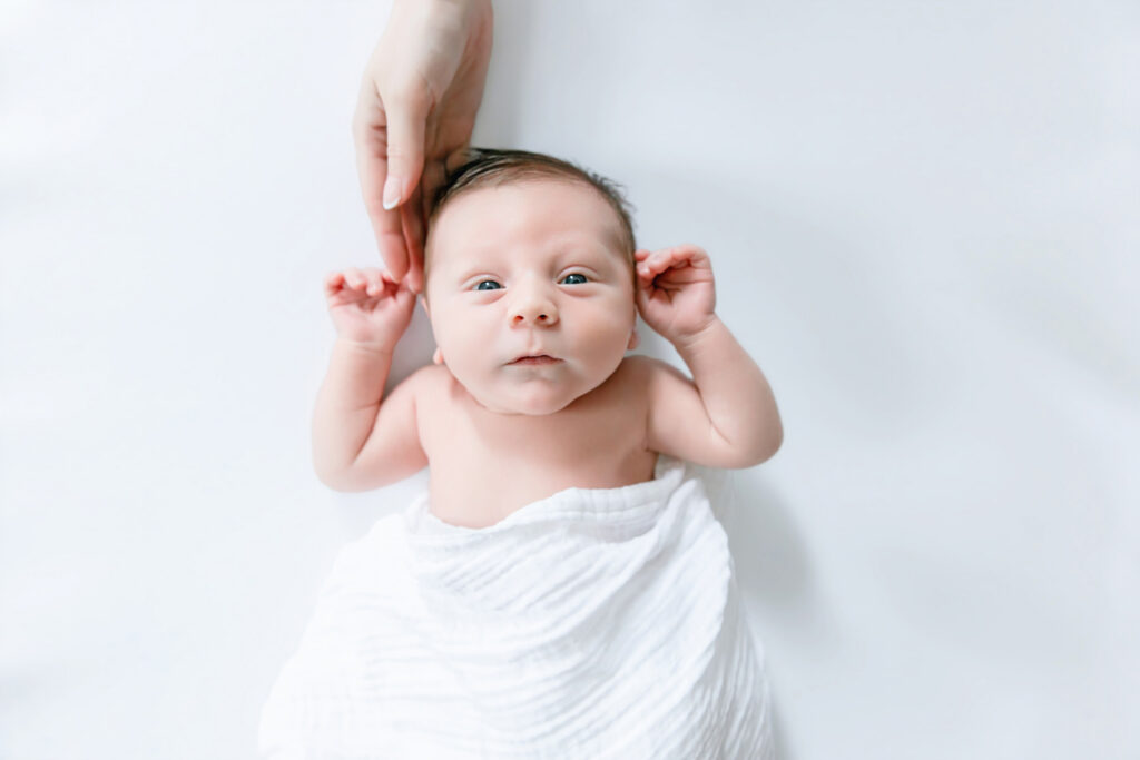 Mom's hand holding side of baby's head during in home newborn session