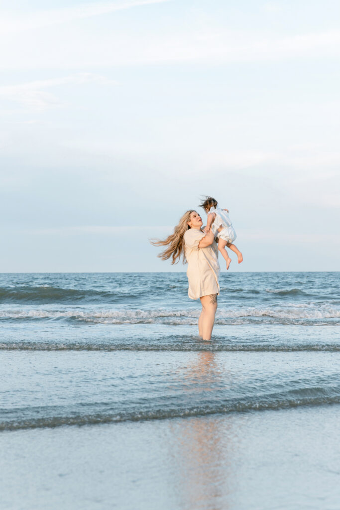 A mom with each of her children in the water at Tybee Island for a lifestyle newborn session.