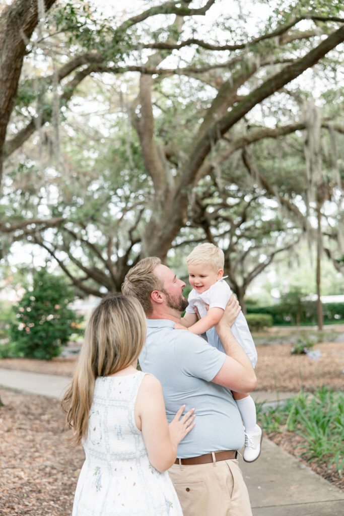Dad holding son while mom looks on during family photos in Savannah