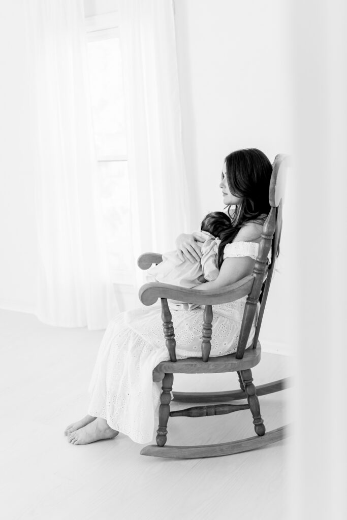 Mom holding her newborn baby in a classic wooden rocking chair