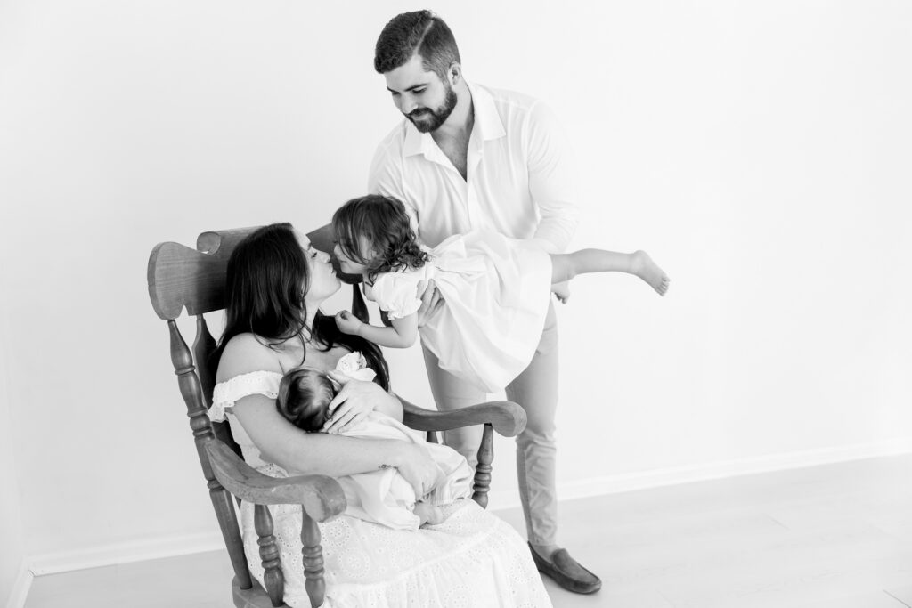 Black-and-white portrait of a family loving on their newborn baby
