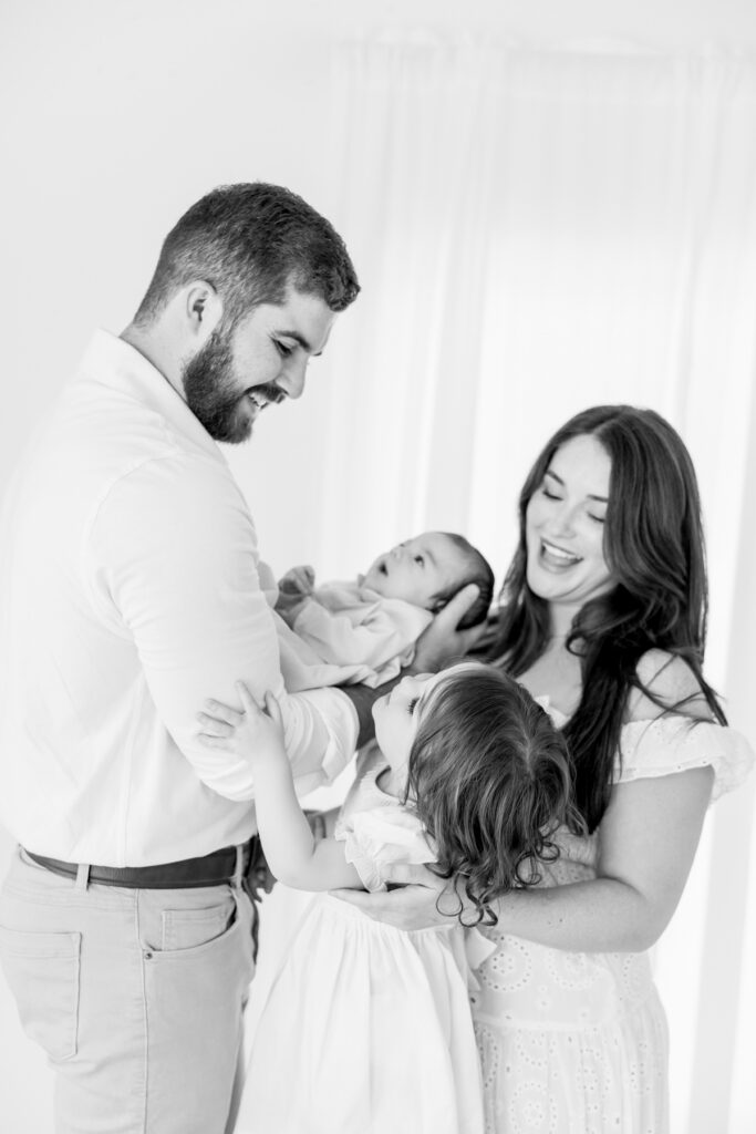 Newborn family photographed together in soft window light at a Savannah studio