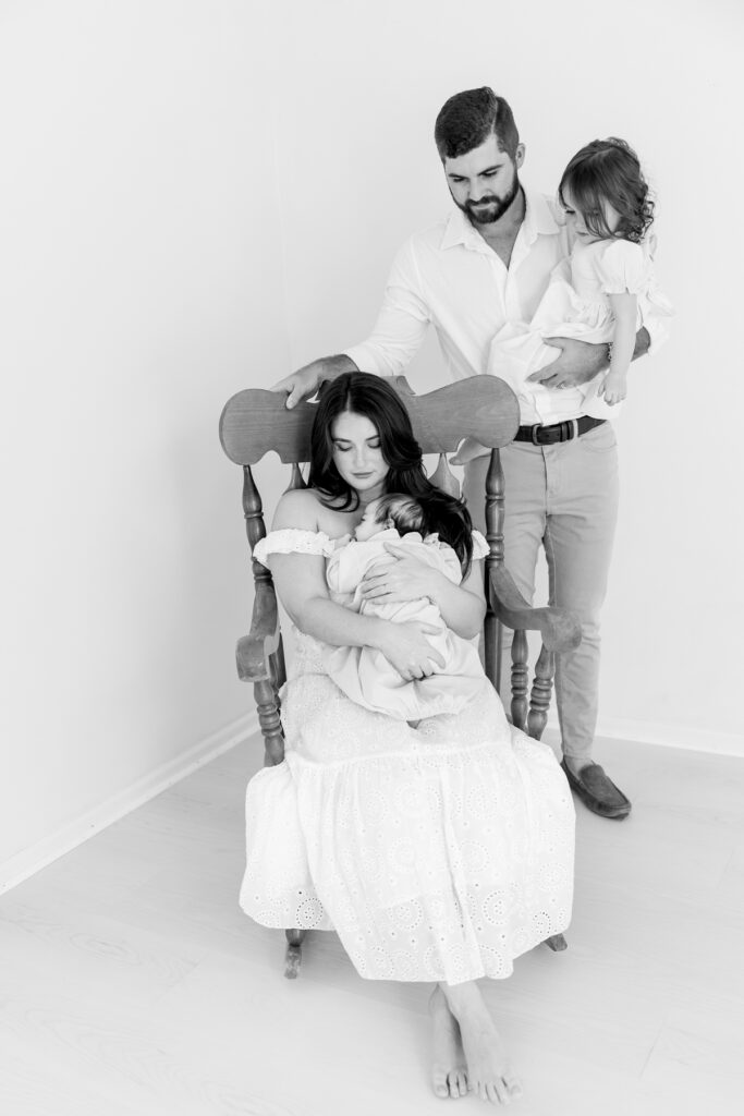 New family of four sharing a quiet moment during newborn portraits
