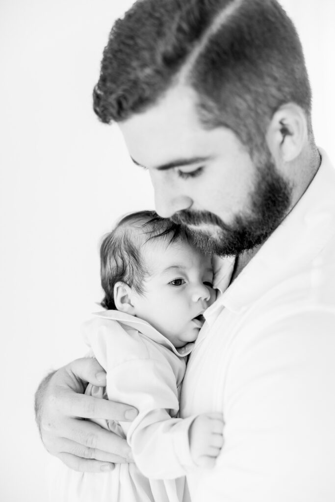 Black-and-white portrait of a father holding his newborn son