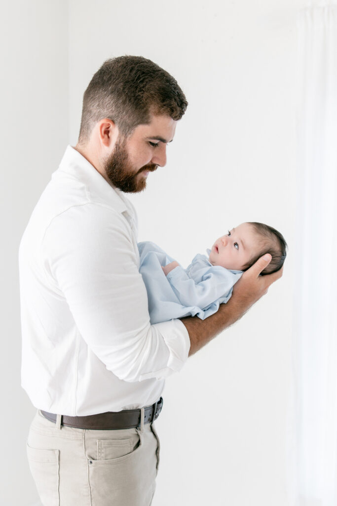 Father gently holding his newborn son during a studio portrait session in Savannah.