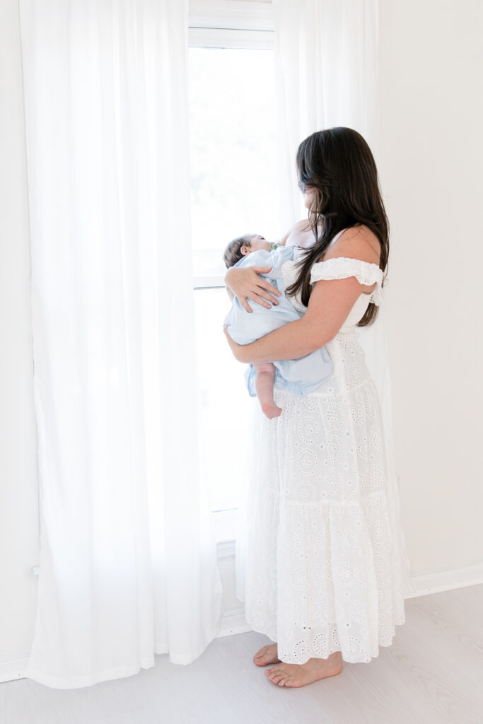 Mom and her newborn son photographed together in soft window light at a Savannah studio