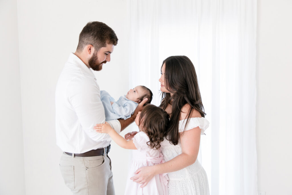 Family loving on their newborn baby in a bright Savannah photography studio