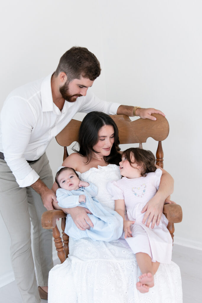 Family gathered with their newborn baby in a classic wooden rocking chair