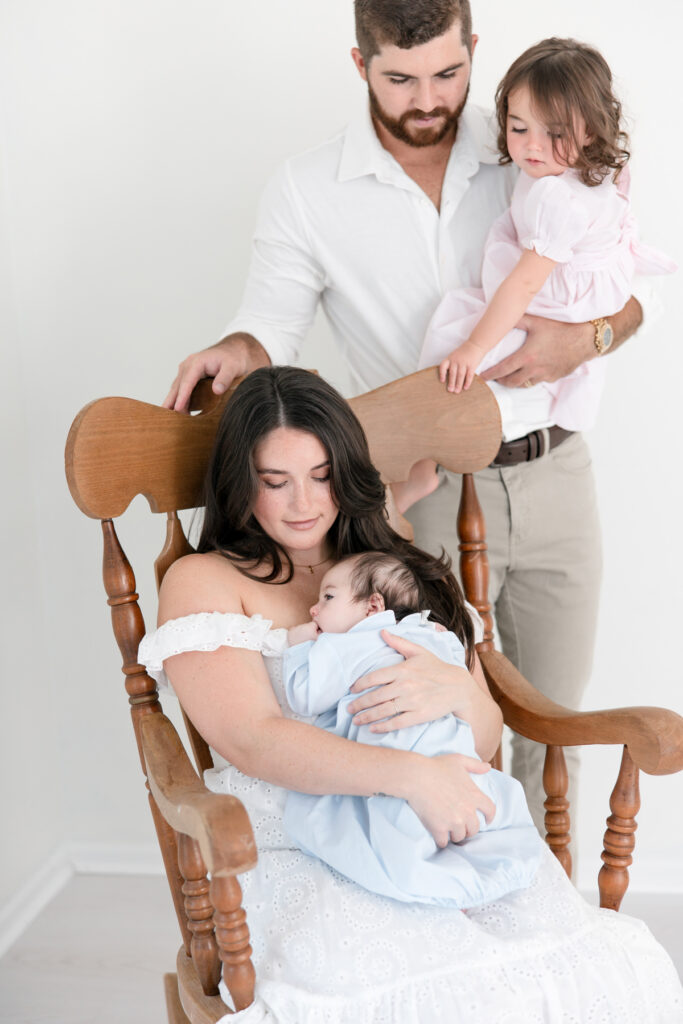 Big sister joining her family for a newborn portrait in the rocking chair